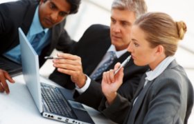 Three business people crowded around a laptop
